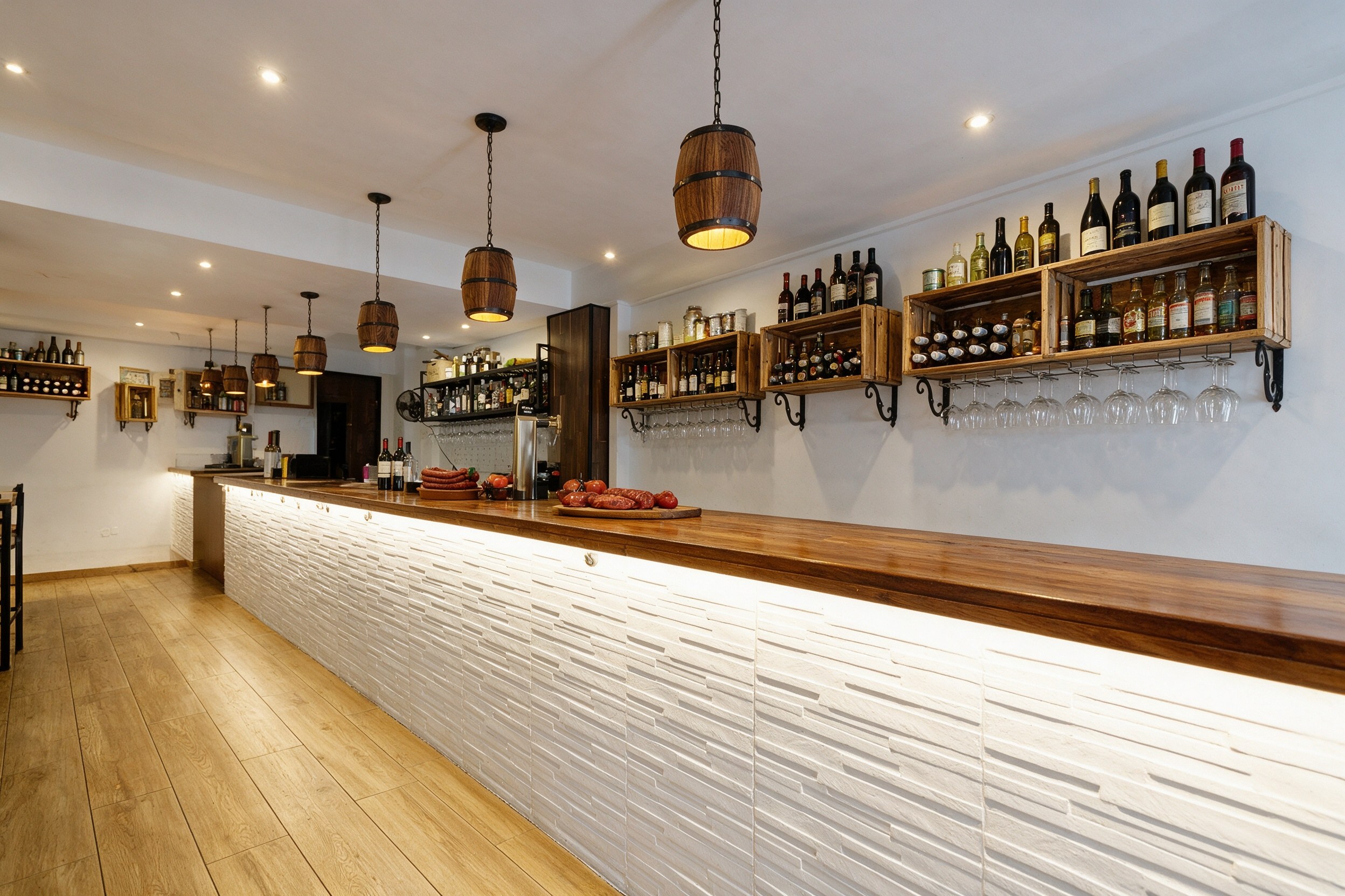 Barra de madera de taberna con estantes de botellas, copas colgadas y lámparas de barrica