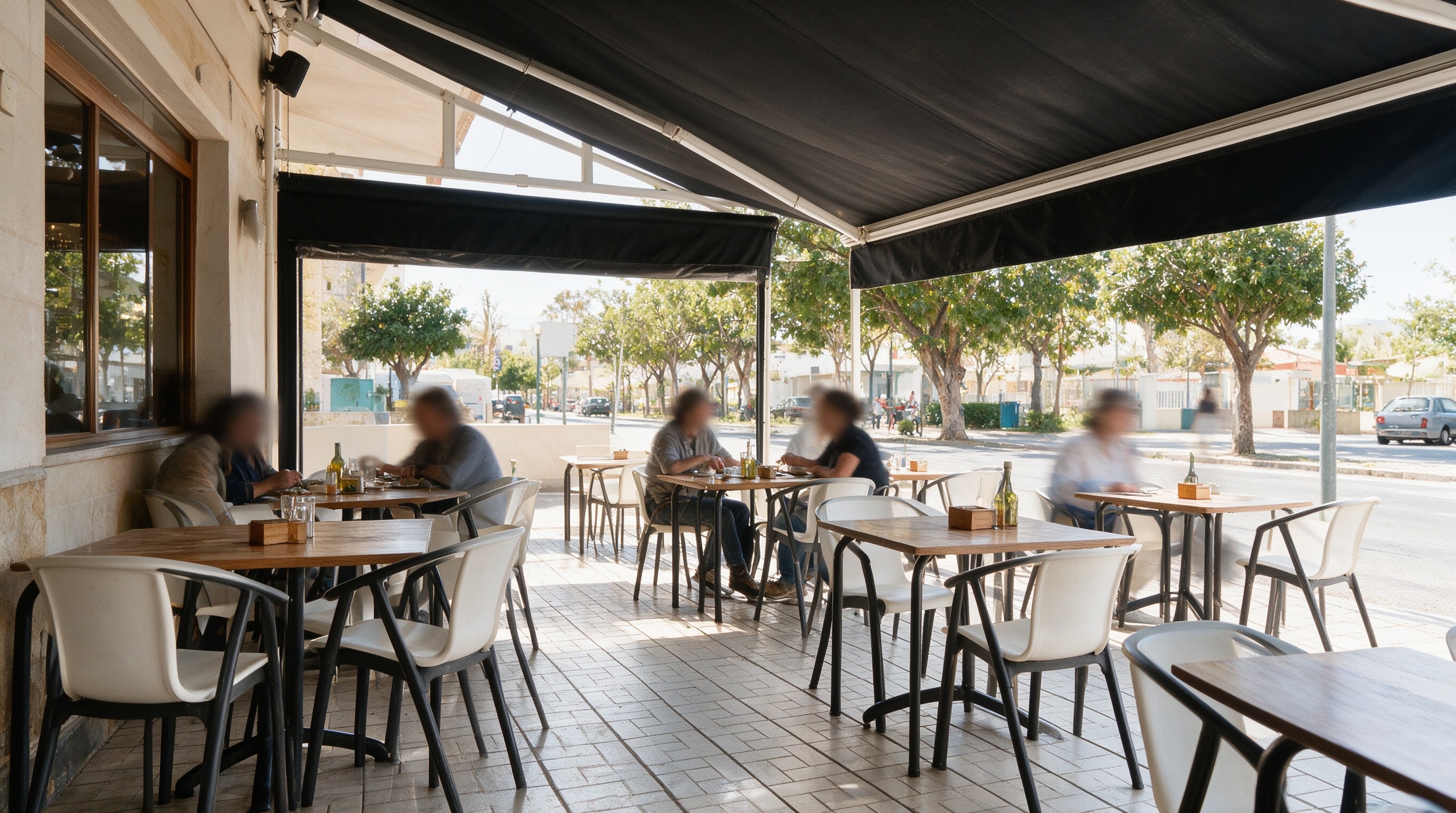 Terraza exterior de taberna bajo toldo negro con mesas y árboles en El Palo